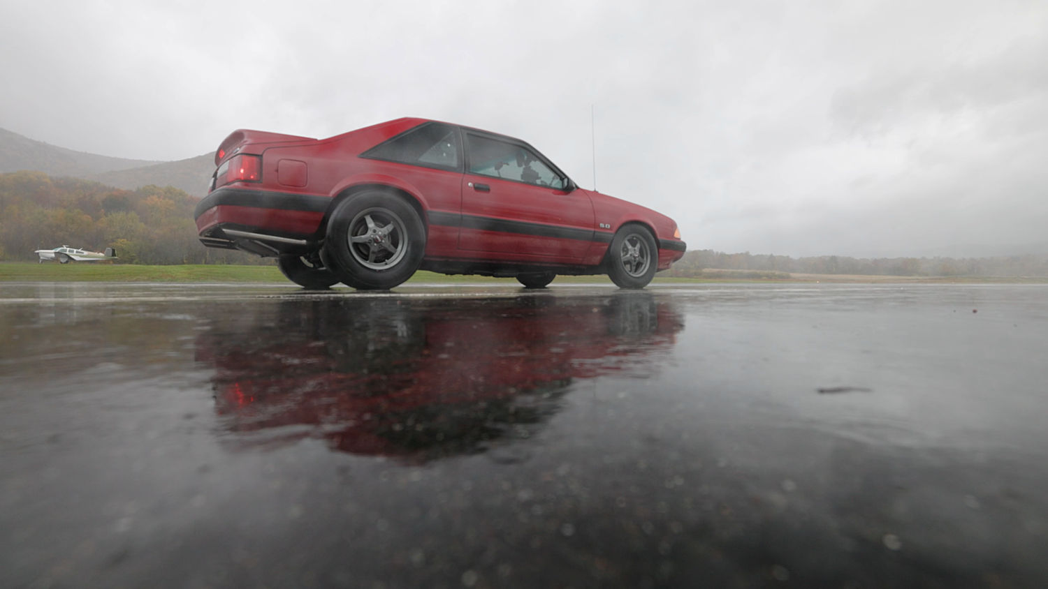 Side view of a red car of a foggy day